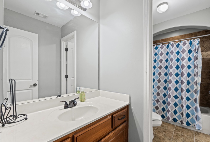 Bathroom with vanity, shower / bathtub combination with curtain, and light tile patterned floors