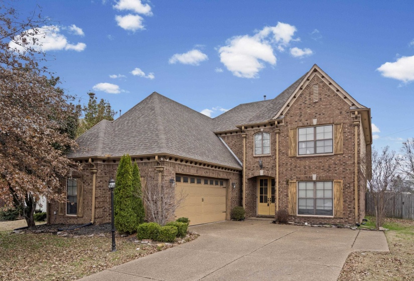French country inspired facade featuring brick siding, roof with shingles, and driveway