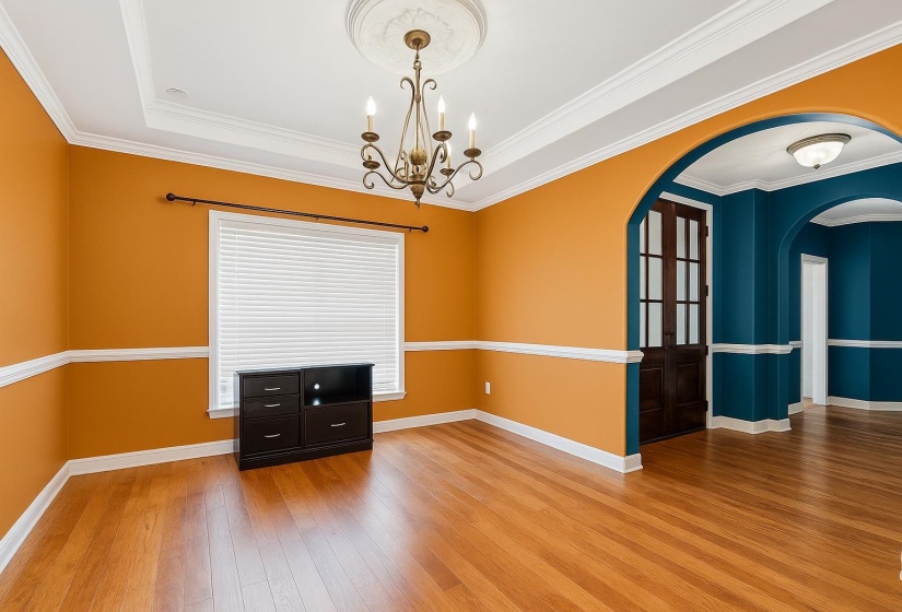 Spare room featuring light wood finished floors, arched walkways, crown molding, and a chandelier