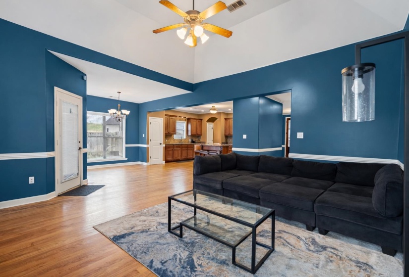 Living room with light wood-style floors, a chandelier, ceiling fan, and high vaulted ceiling