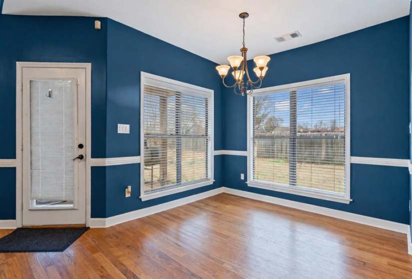Unfurnished dining area featuring wood finished floors and a chandelier