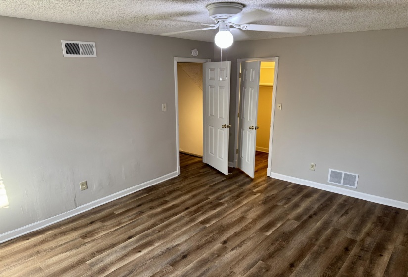 Unfurnished bedroom featuring a textured ceiling, a ceiling fan, and dark wood-style flooring