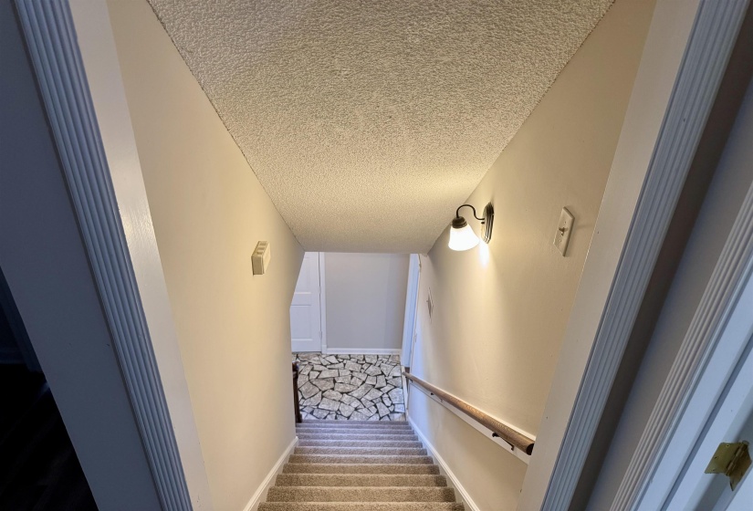 Stairway featuring carpet floors and a textured ceiling