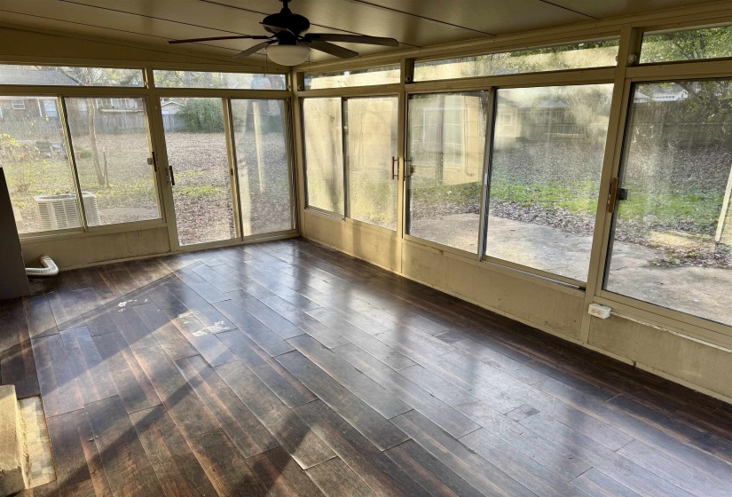 Unfurnished sunroom with ceiling fan, wood finished floors, and vaulted ceiling