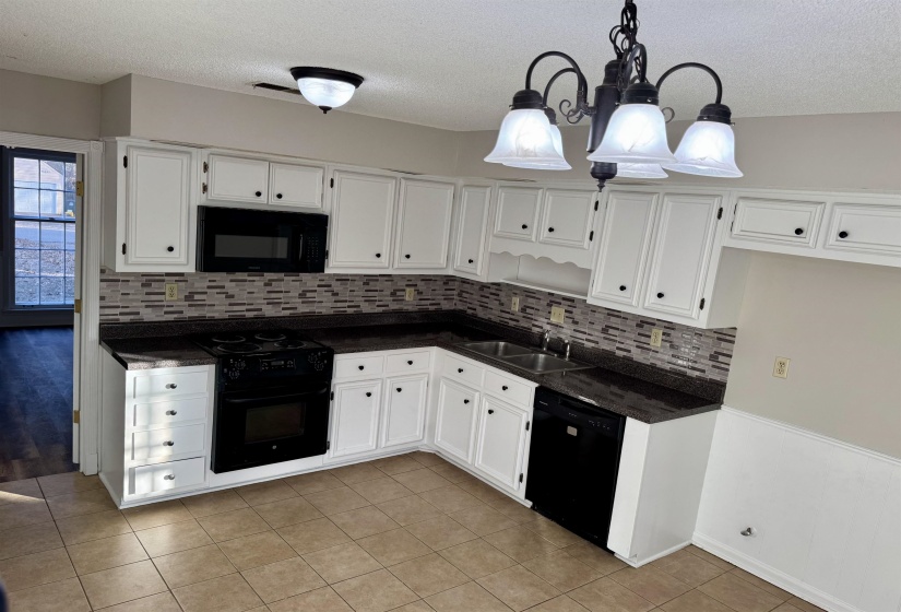 Kitchen featuring white cabinetry, pendant lighting, black appliances, a textured ceiling, and light tile patterned floors