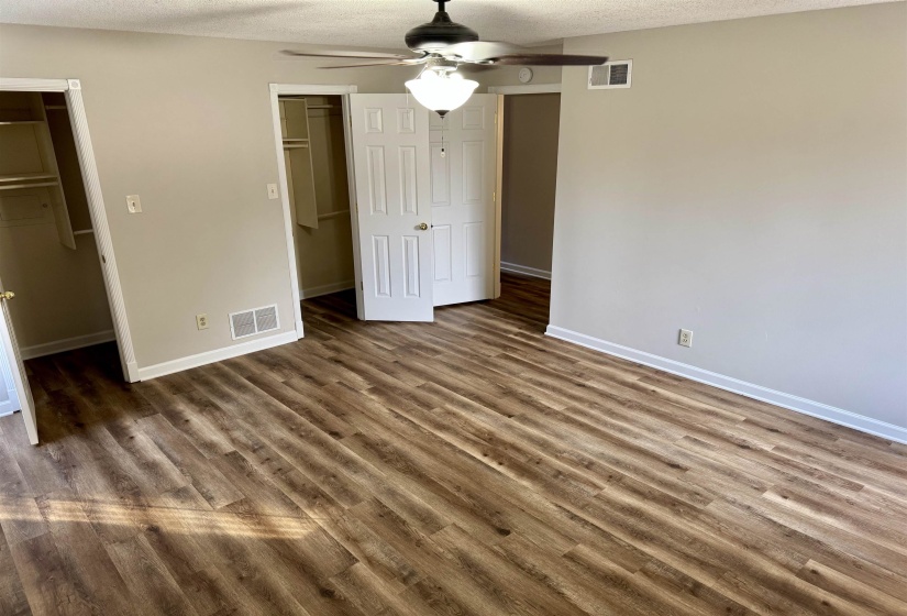 Unfurnished bedroom featuring a walk in closet, a textured ceiling, a ceiling fan, and wood finished floors