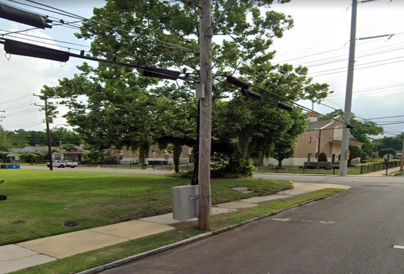 View of asphalt road featuring curbs and sidewalks