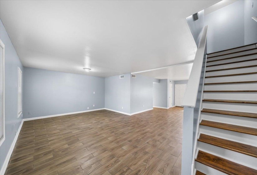 Unfurnished living room with wood finished floors and stairs