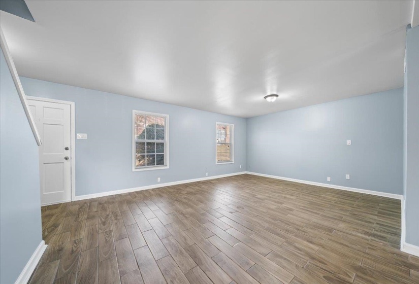 Unfurnished living room featuring wood tiled floors and baseboards
