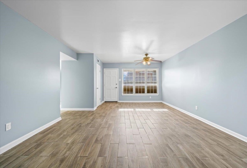 Unfurnished living room featuring wood tiled floors and a ceiling fan