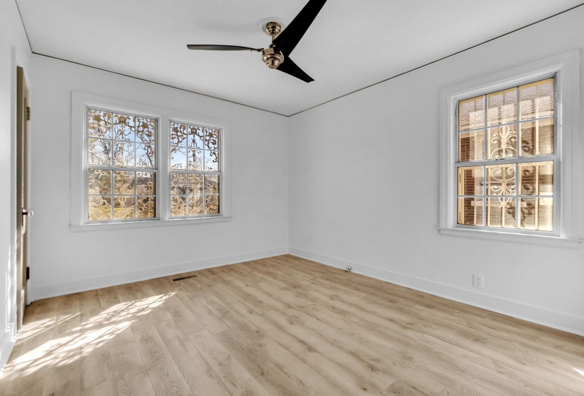Empty room featuring light wood-type flooring, healthy amount of natural light, and a ceiling fan