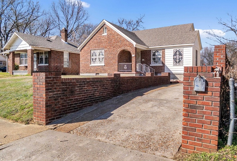 View of front facade featuring brick siding, a chimney, a shingled roof, and covered porch