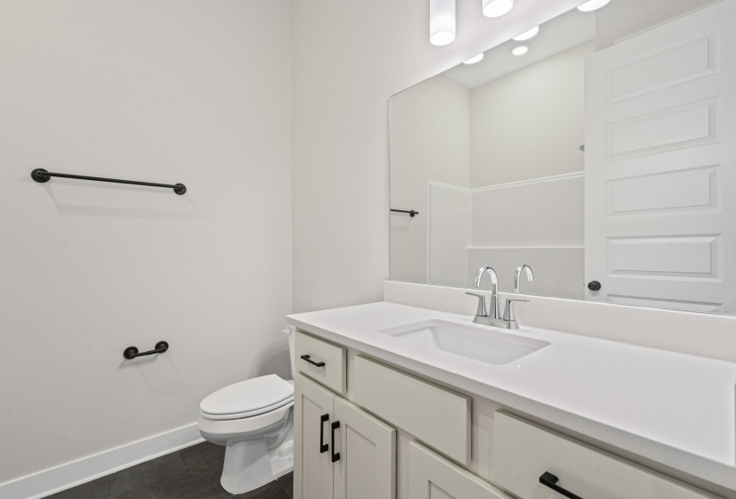 Bathroom featuring a white vanity with recessed panel cabinetry and matte black hardware, a rectangular undermount sink, and a single-handle chrome faucet