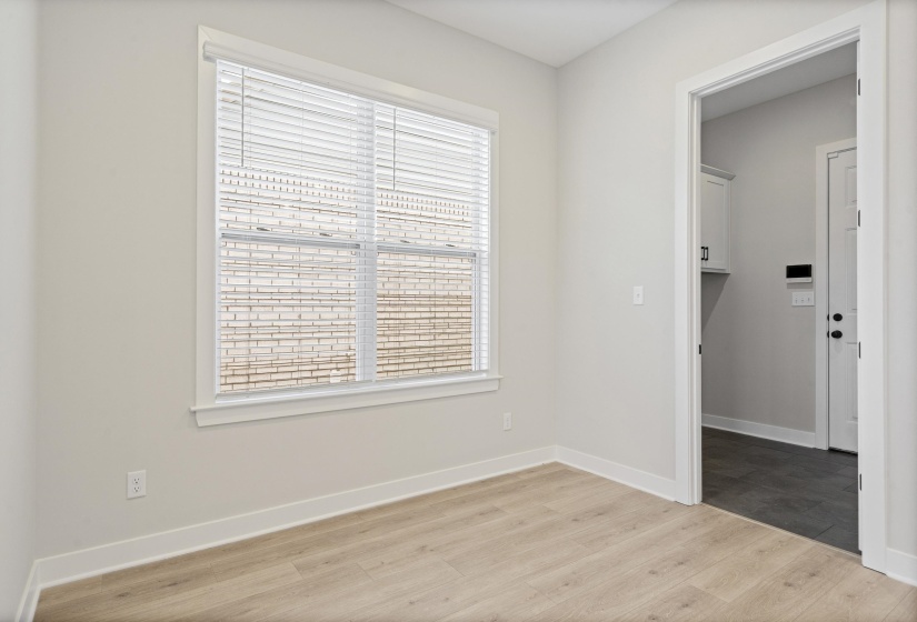 Neutral-toned room featuring light wood-finish flooring, a double window with blinds, and white trim