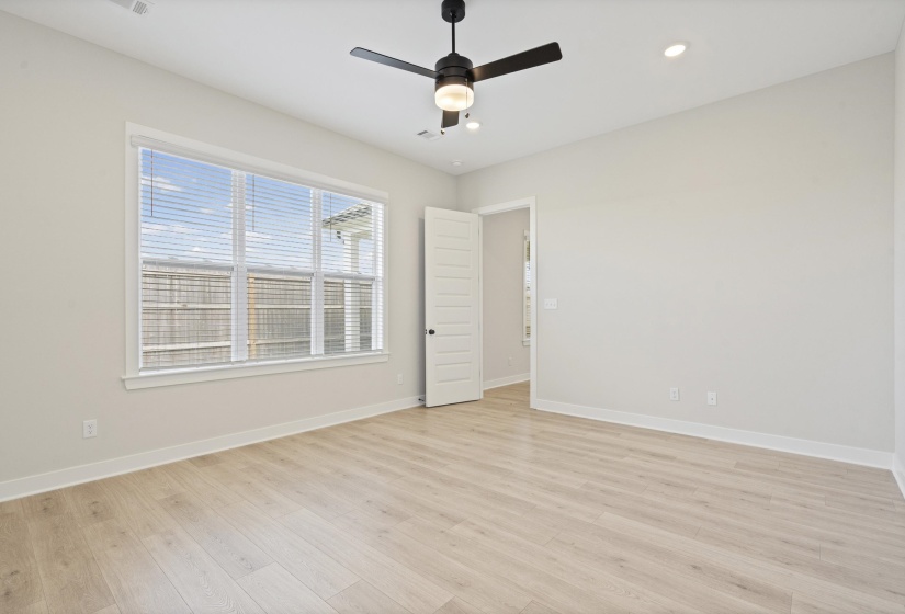 Spacious room featuring wood-finish flooring, a large window with blinds, and white trim