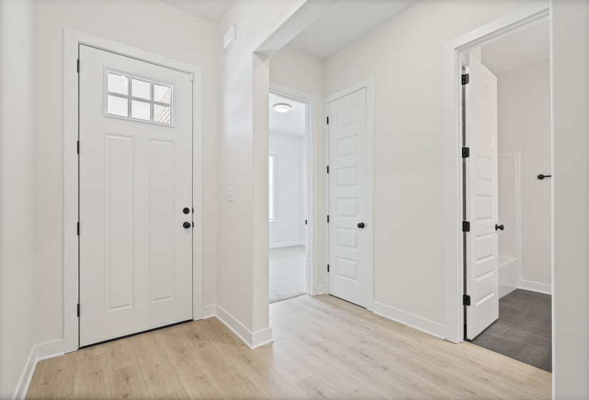 Entryway featuring a white paneled door with an upper window insert, matte black hardware, and wood-finish flooring