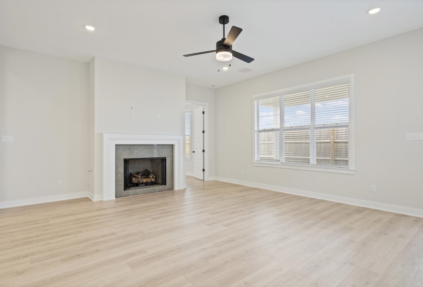 Spacious living area featuring light wood-finish flooring, a contemporary ceiling fan, and recessed lighting