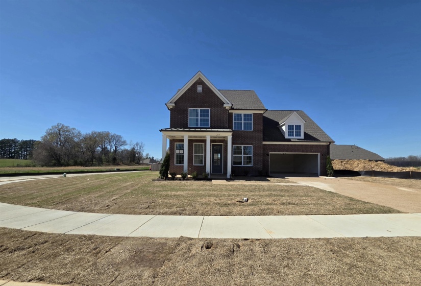 View of front of property featuring brick siding, covered porch, concrete driveway, a garage, and a front yard