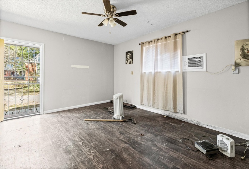 Unfurnished room featuring a textured ceiling, wood finished floors, ceiling fan, radiator, and a wall mounted air conditioner