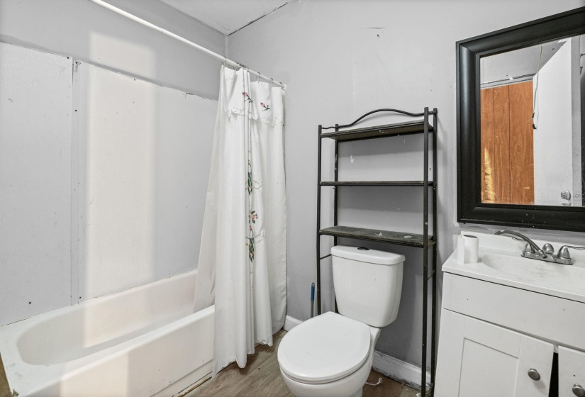 Bathroom with shower / bath combination with curtain, vanity, and wood finished floors
