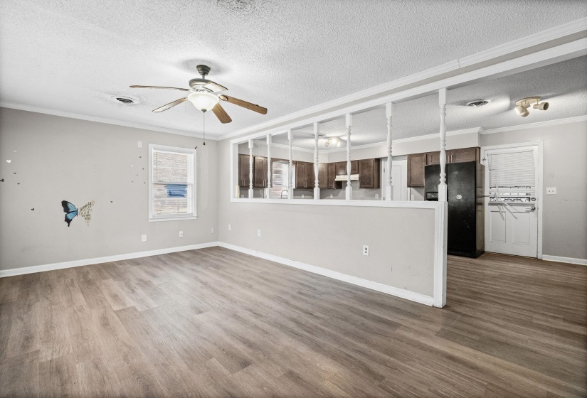 Unfurnished living room with ornamental molding, a textured ceiling, dark wood-style floors, and ceiling fan