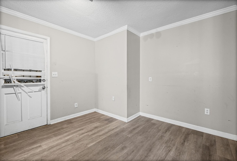 Unfurnished room with a textured ceiling, wood finished floors, and ornamental molding