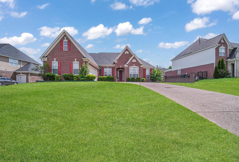 Brick exterior residence featuring red decorative shutters, white window trim, a prominent front gable, and an attached two-car garage