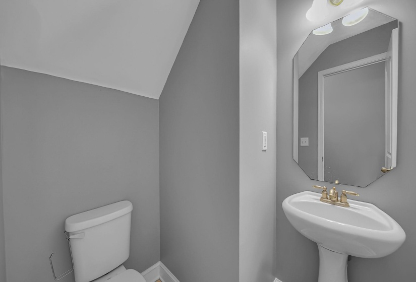 Pedestal sink with brass-finish faucet and an octagonal wall-mounted mirror