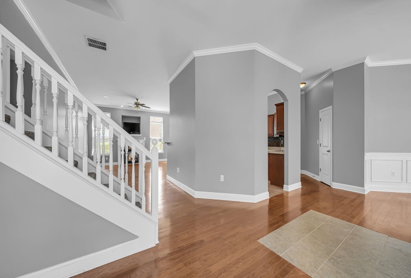 Entryway featuring wood-finish flooring, white trim, and a staircase with white balusters