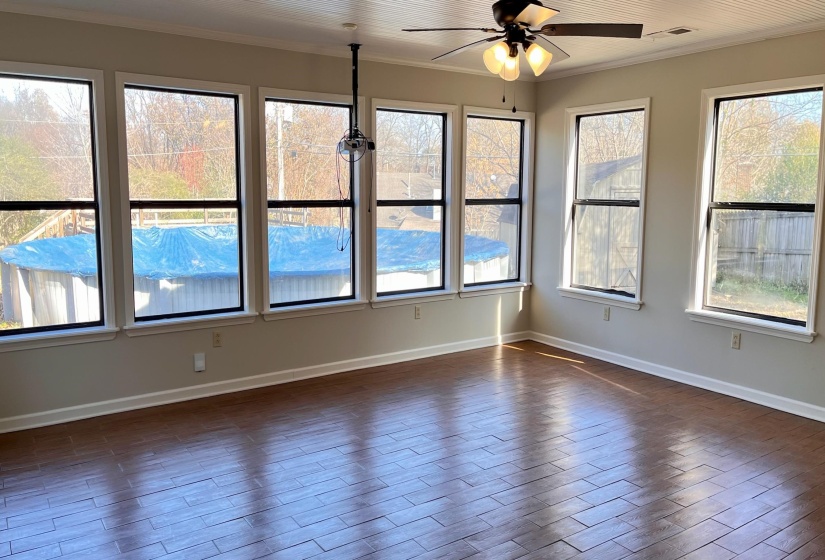 Unfurnished rec room featuring wood tiled floors, crown molding, and healthy amount of natural light