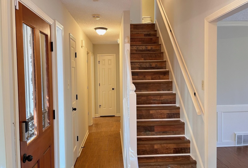 Staircase featuring a textured ceiling and wood finished floors