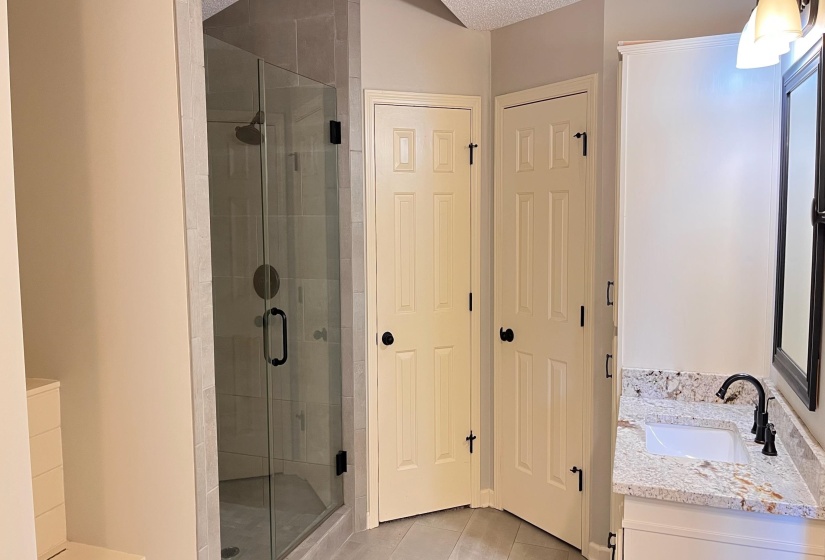 Bathroom featuring vanity, light tile patterned flooring, a stall shower, and a textured ceiling