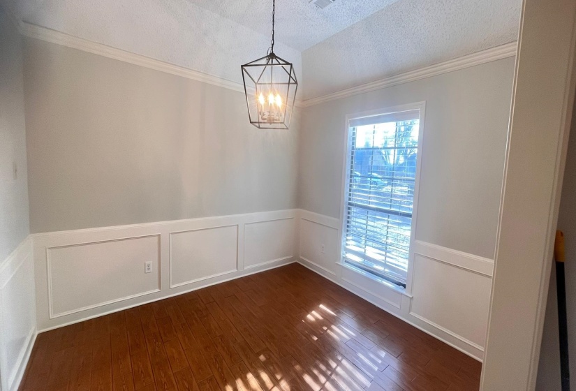 Unfurnished room with wainscoting, a decorative wall, dark wood-type flooring, a textured ceiling, and crown molding