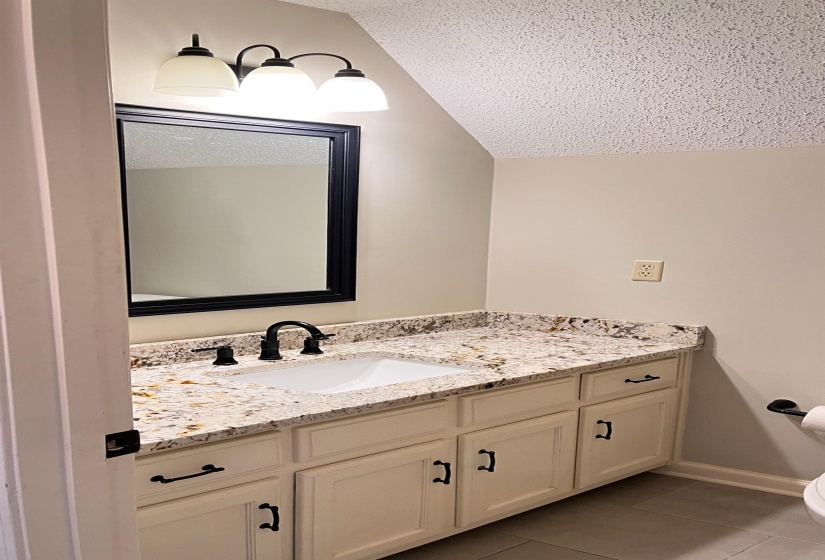 3rd Full bathroom featuring vanity, a textured ceiling, light tile patterned floors, and vaulted ceiling