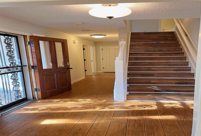Entrance foyer with stairs, hardwood / wood-style floors, a textured ceiling, and plenty of natural light