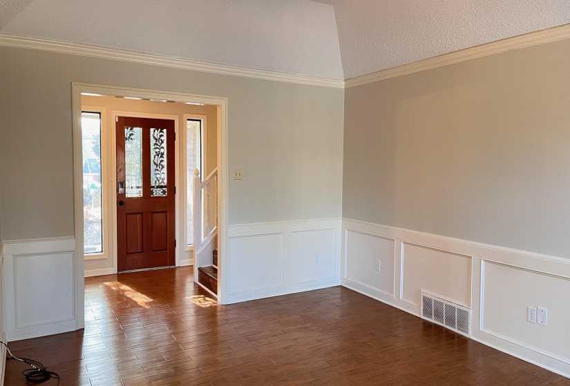 Entryway featuring a wainscoted wall, ornamental molding, a decorative wall, dark wood-type flooring, and stairway