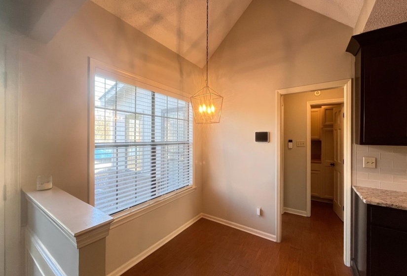 Unfurnished dining area with a chandelier, dark wood-style floors, and high vaulted ceiling