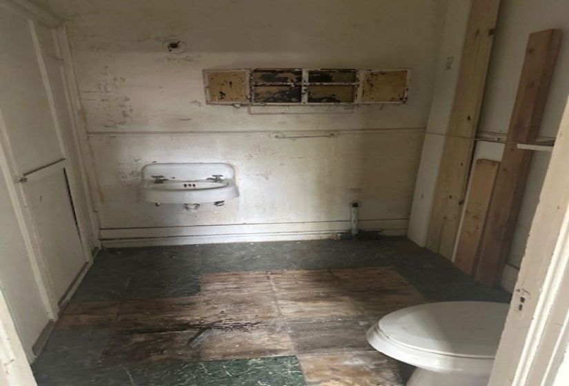 Compact room featuring a wall-mounted sink, a toilet, and a built-in wall cabinet with multiple compartments