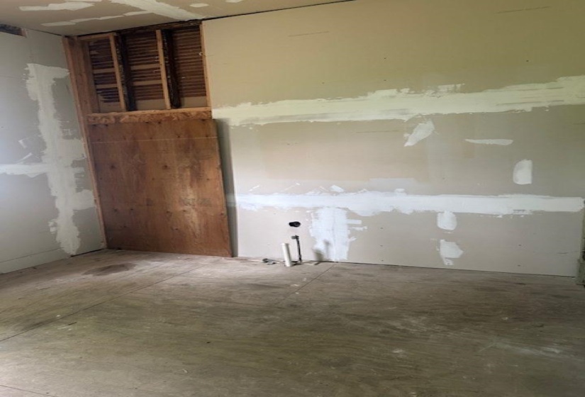 Room featuring exposed wall studs and unfinished drywall, with visible plumbing rough-ins