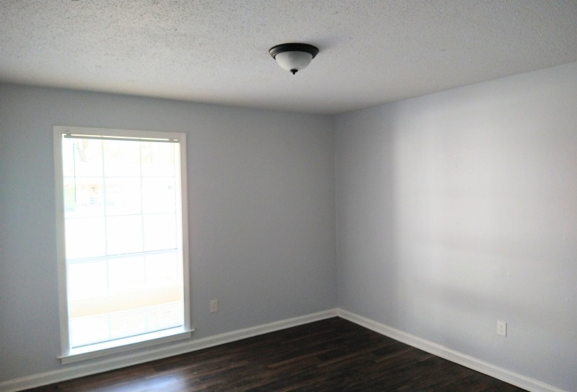 Unfurnished bedroom featuring a textured ceiling and dark wood-style flooring