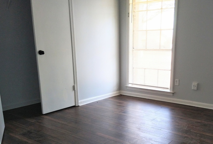 Unfurnished bedroom featuring healthy amount of natural light, double door closet and dark wood-style floors