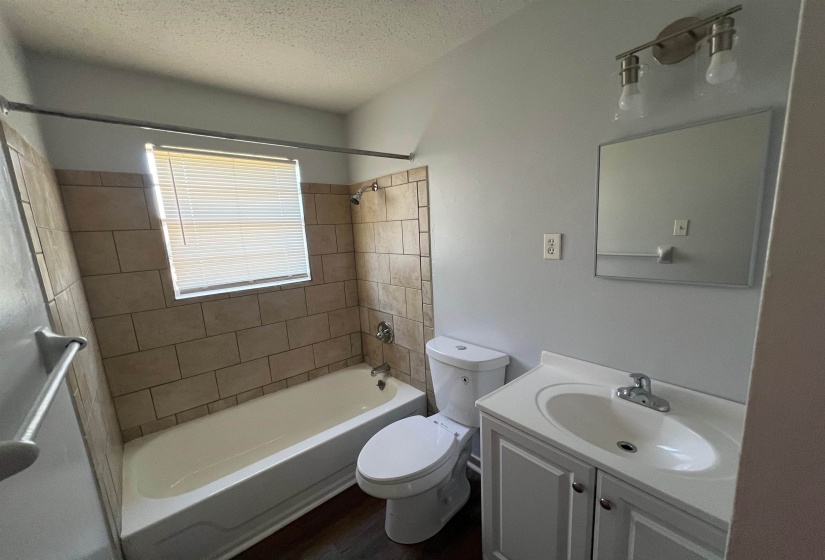 Bathroom with vanity,  shower combination, a textured ceiling, and dark wood-style flooring