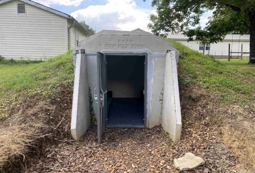 Concrete storm shelter with an arched concrete entrance and a metal door