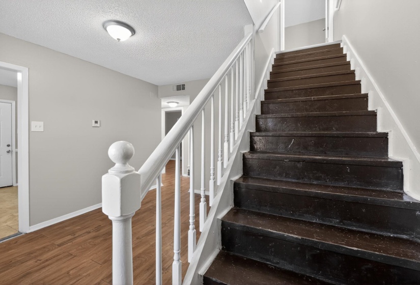 Staircase with wood finished floors and a textured ceiling