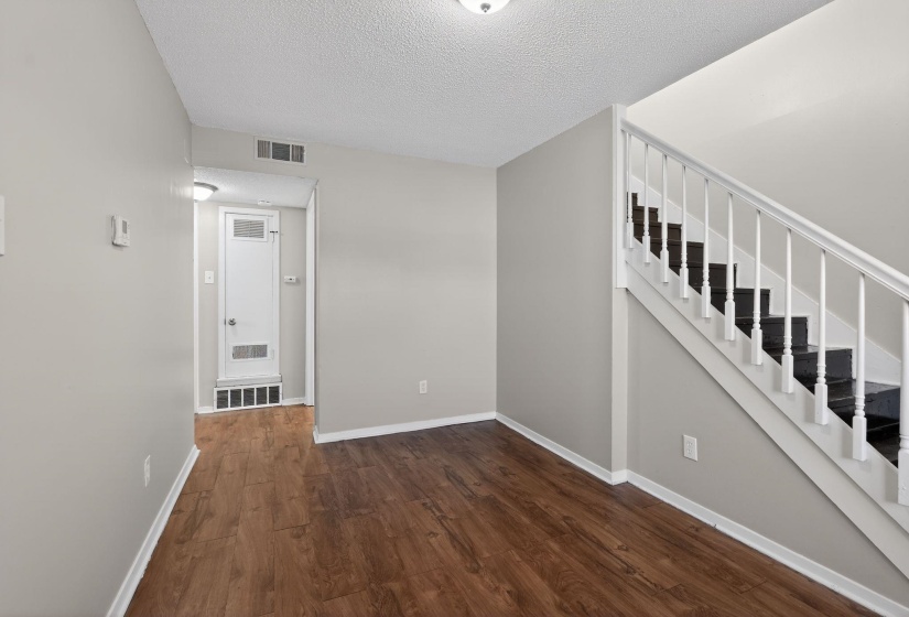 Unfurnished living room featuring stairway, dark wood finished floors, and a textured ceiling