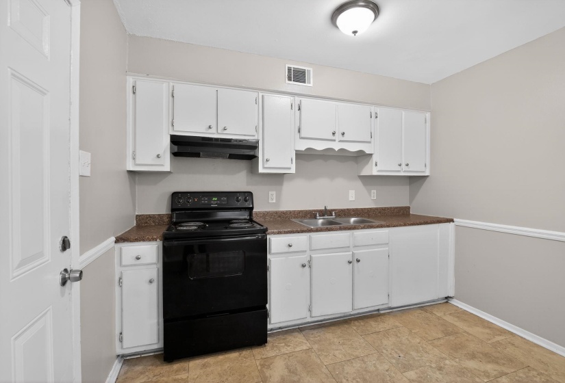Kitchen featuring black range with electric stovetop, dark countertops, white cabinets, and under cabinet range hood