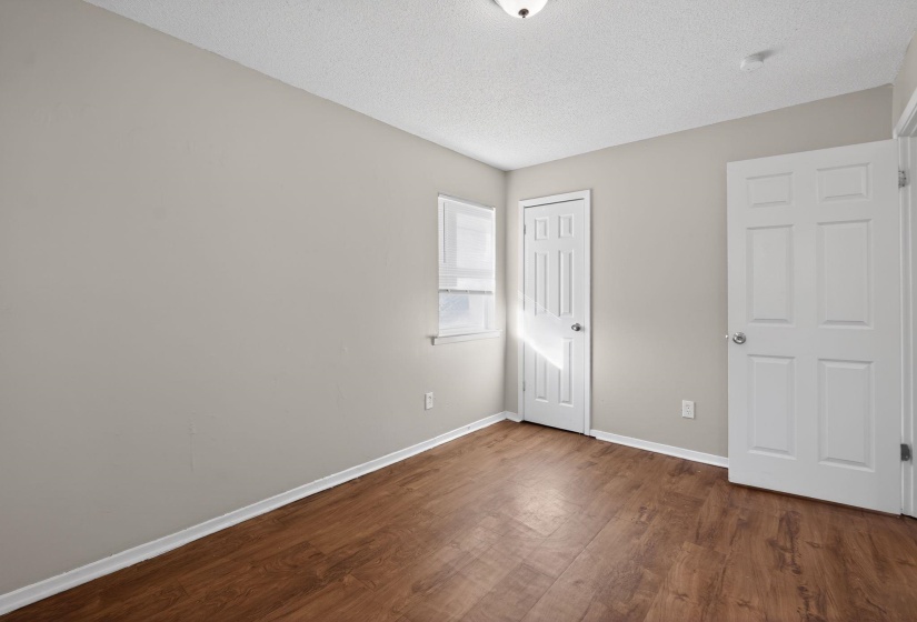 Unfurnished bedroom featuring a textured ceiling, dark wood-type flooring, and a closet