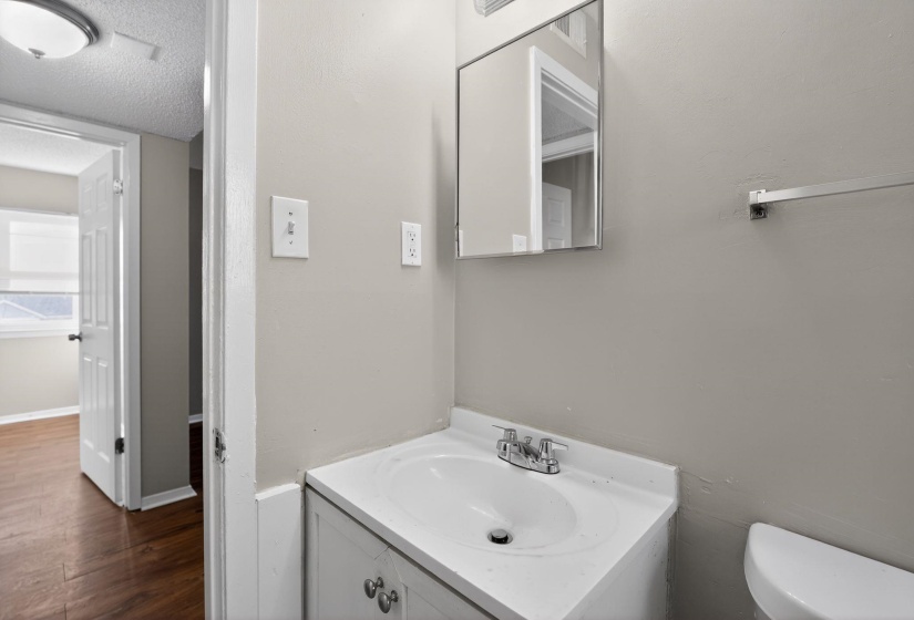 Half bath with vanity, a textured ceiling, and dark wood-style flooring