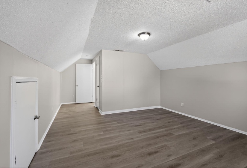 Bonus room featuring lofted ceiling, a textured ceiling, and wood finished floors