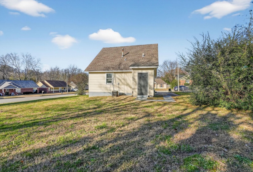Back of property featuring a lawn and roof with shingles